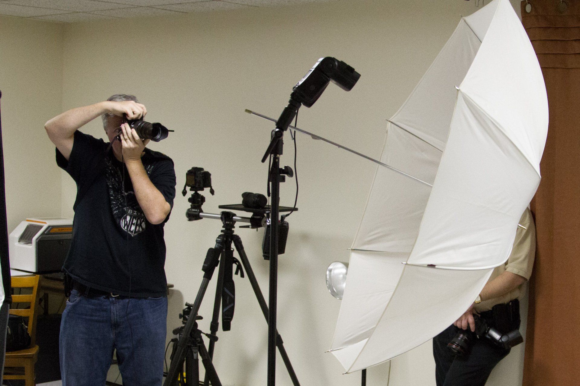 A photographer taking pictures in a studio with a speedlight and shoot through umbrella.