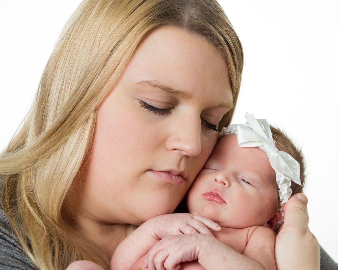 A studio portrait of a mother holding her infant child in her arms and her eyes closed against a white backgroundAn outdoor portrait of a couple out of focus in the distance with illuminated heart in focus in the foreground