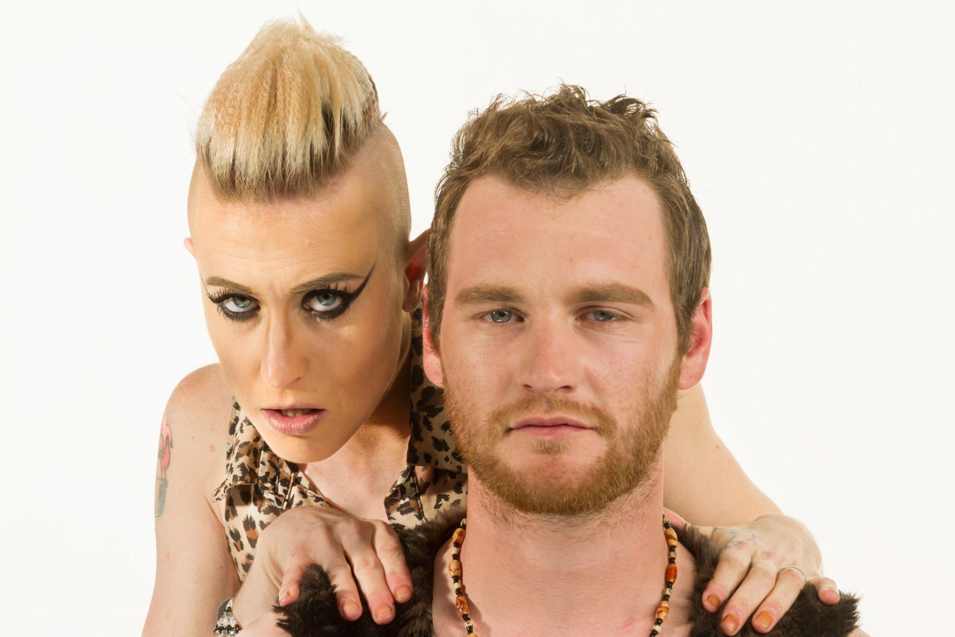 A man and woman posing together for a styled shoot against a white background.