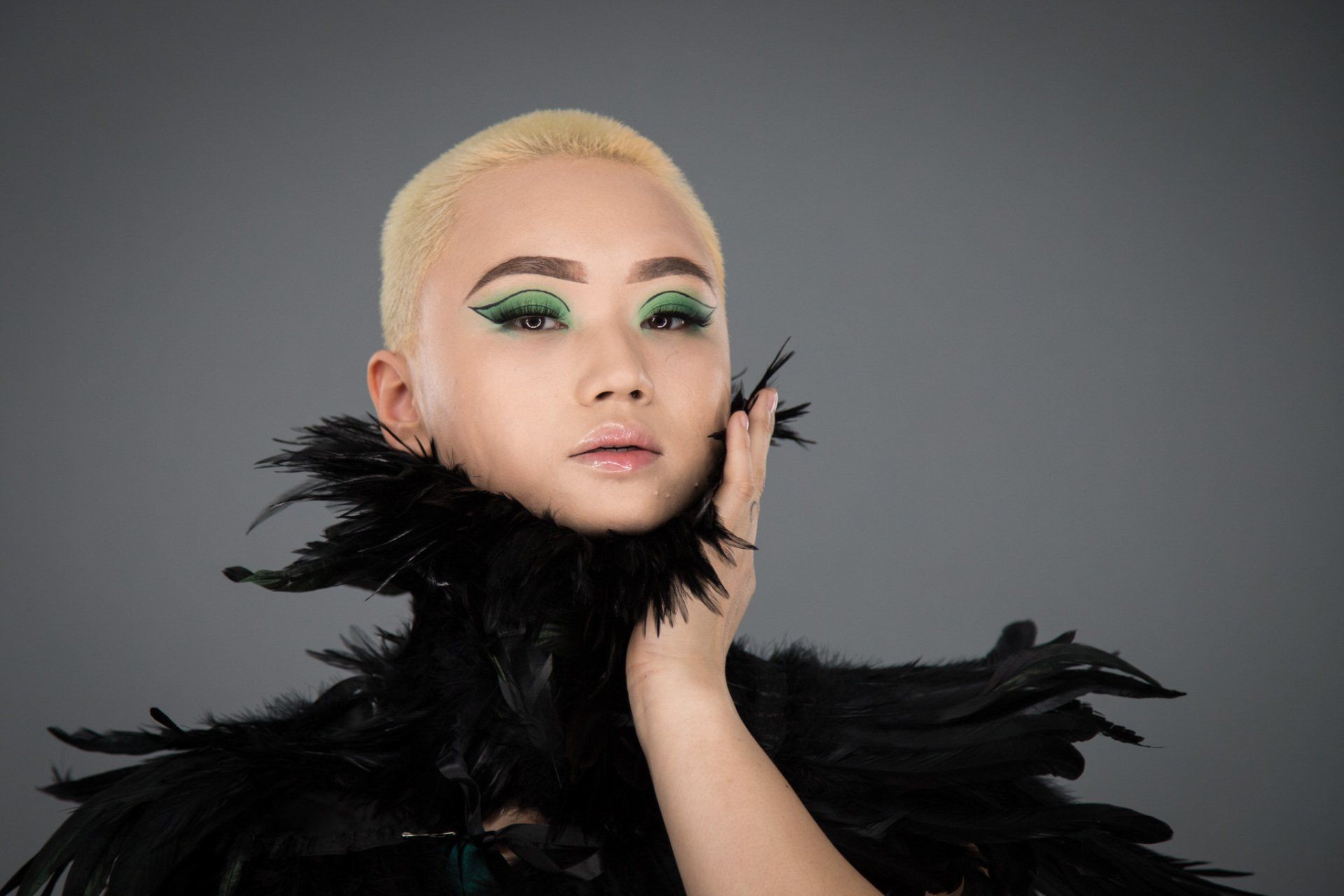 A woman in a black top and boa with black feathers posed for a styled fashion shoot.