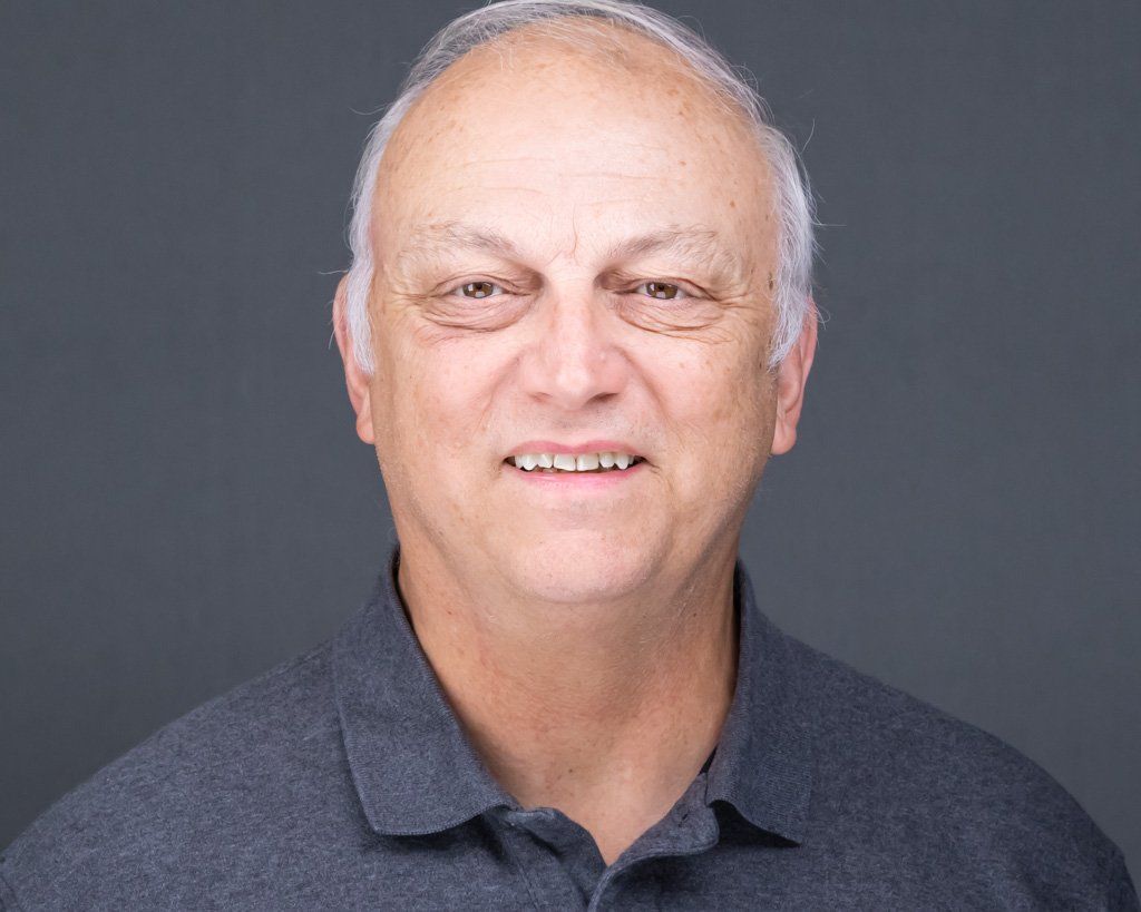 A headshot of man in a grey polo shirt