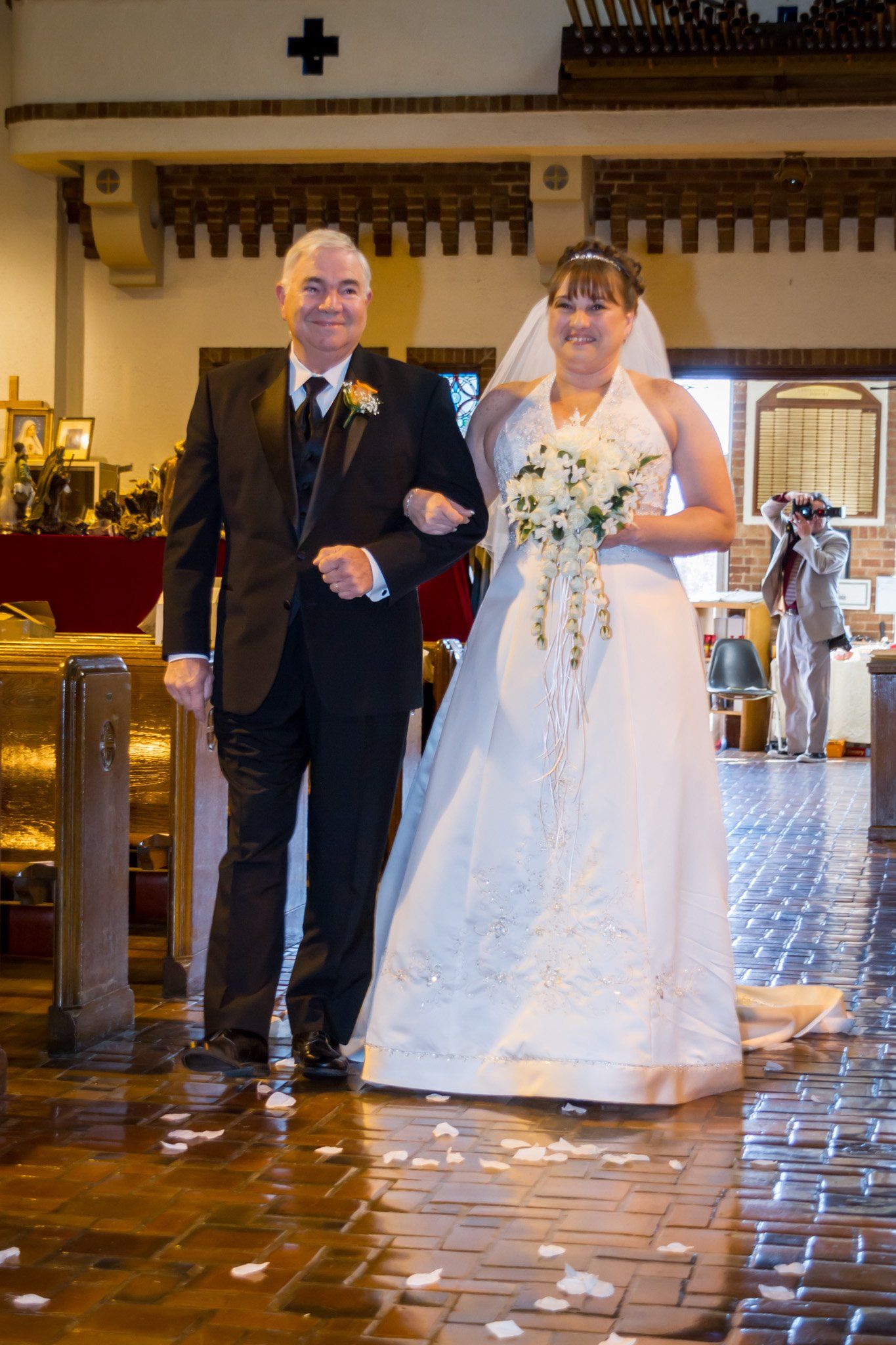 A bride being walked down the aisle of a church by her father