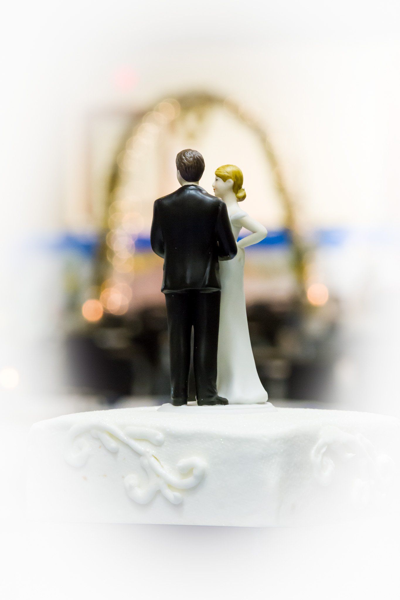 An artistic image of a wedding cake top with bride and groom figures