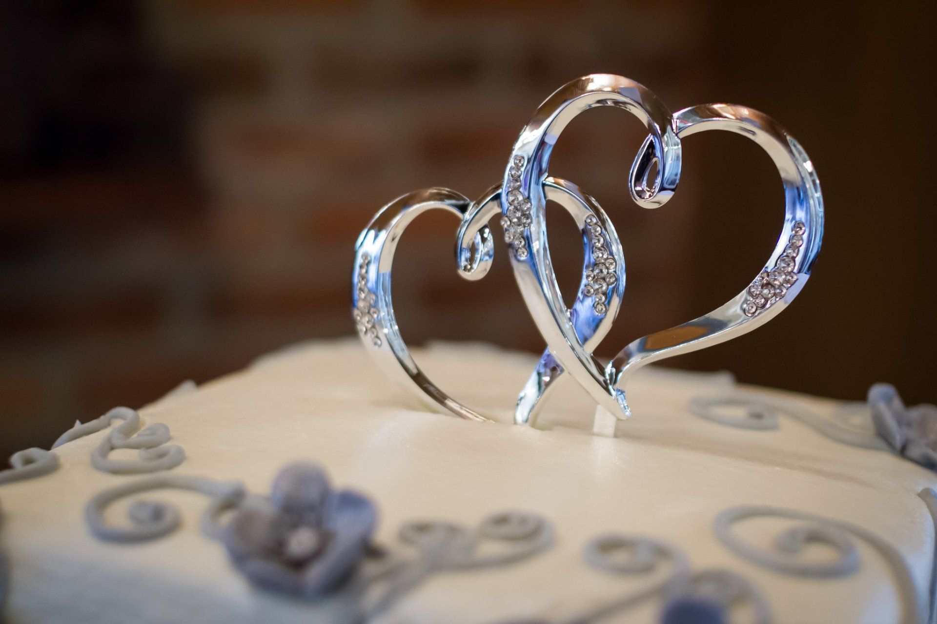 A picture of silver interlocking hearts on top of a wedding cake