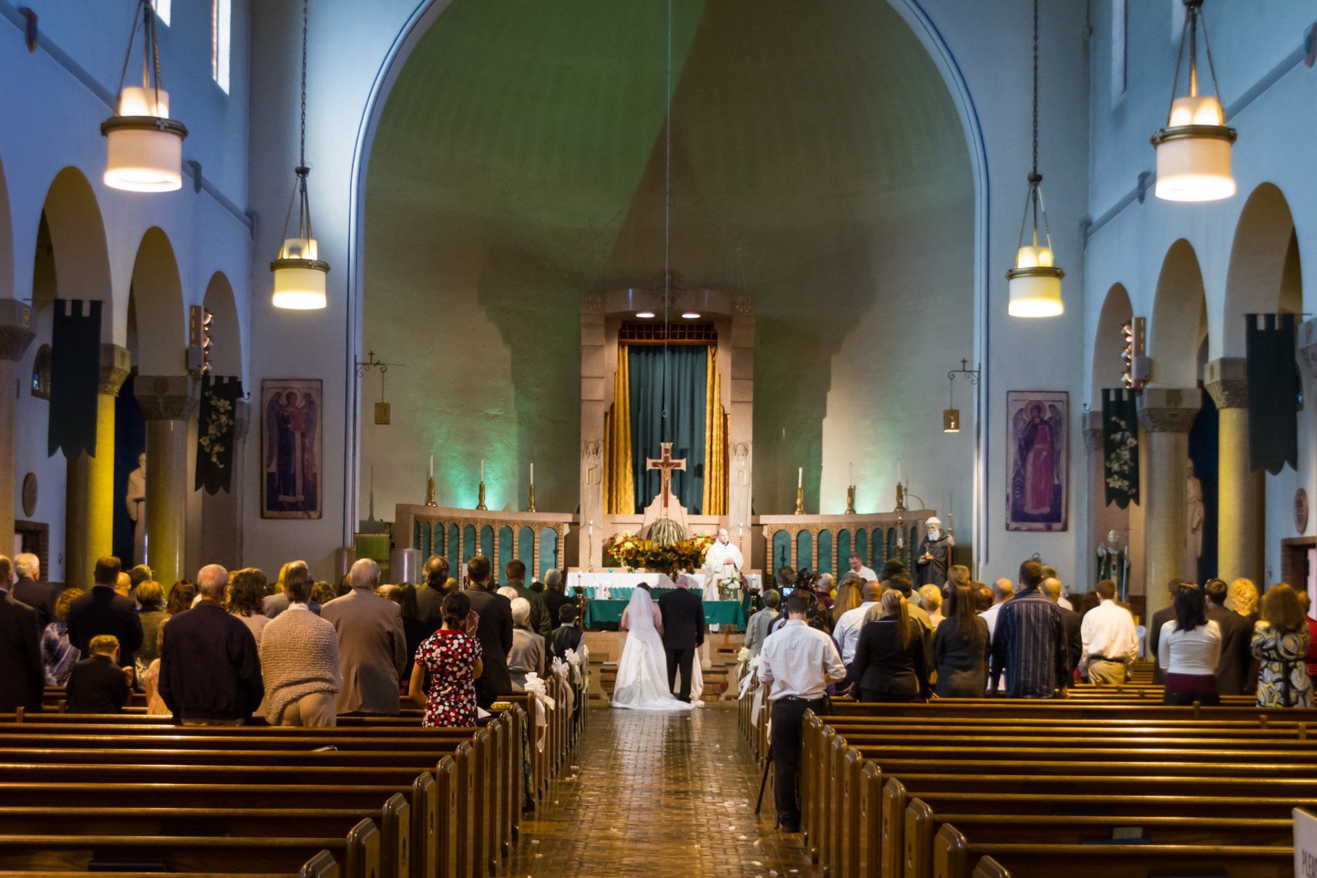 A view from the back of the church of the aisle, the bride and groom at the alter and the church in the background