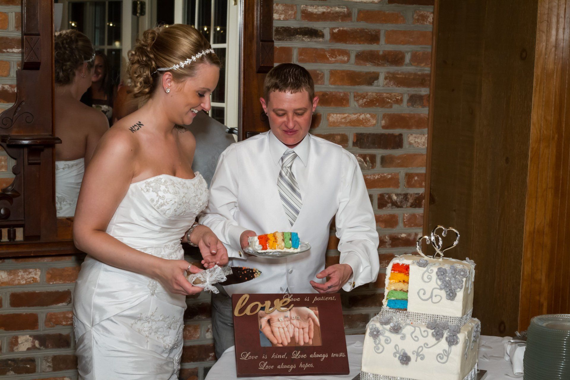 A picture of LGBTQ couple cutting their rainbow colored wedding cake