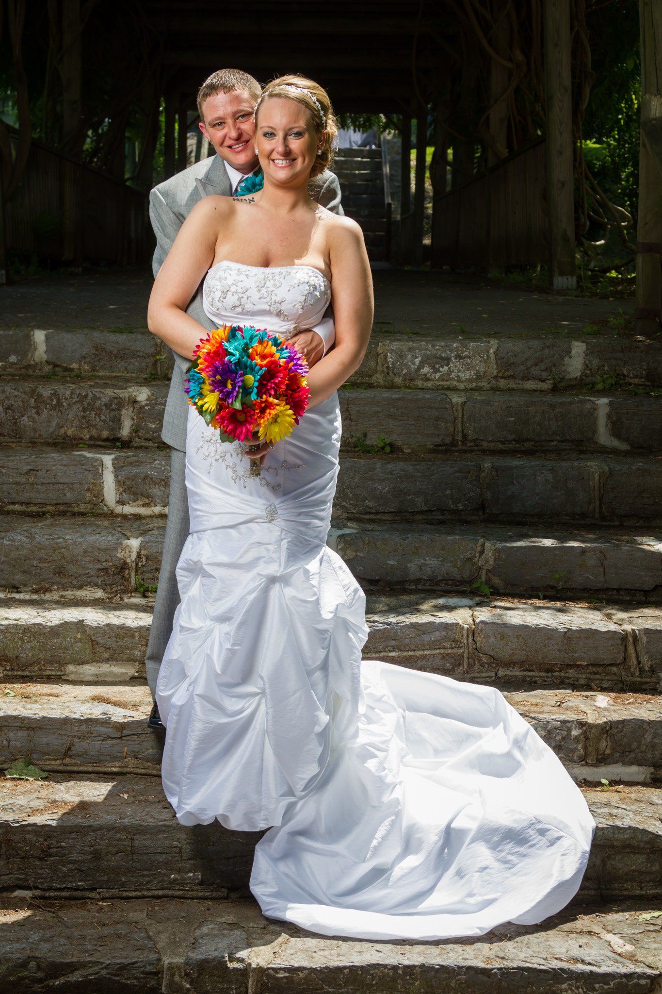 An outdoor portrait of a newly married couple standing together on concrete steps