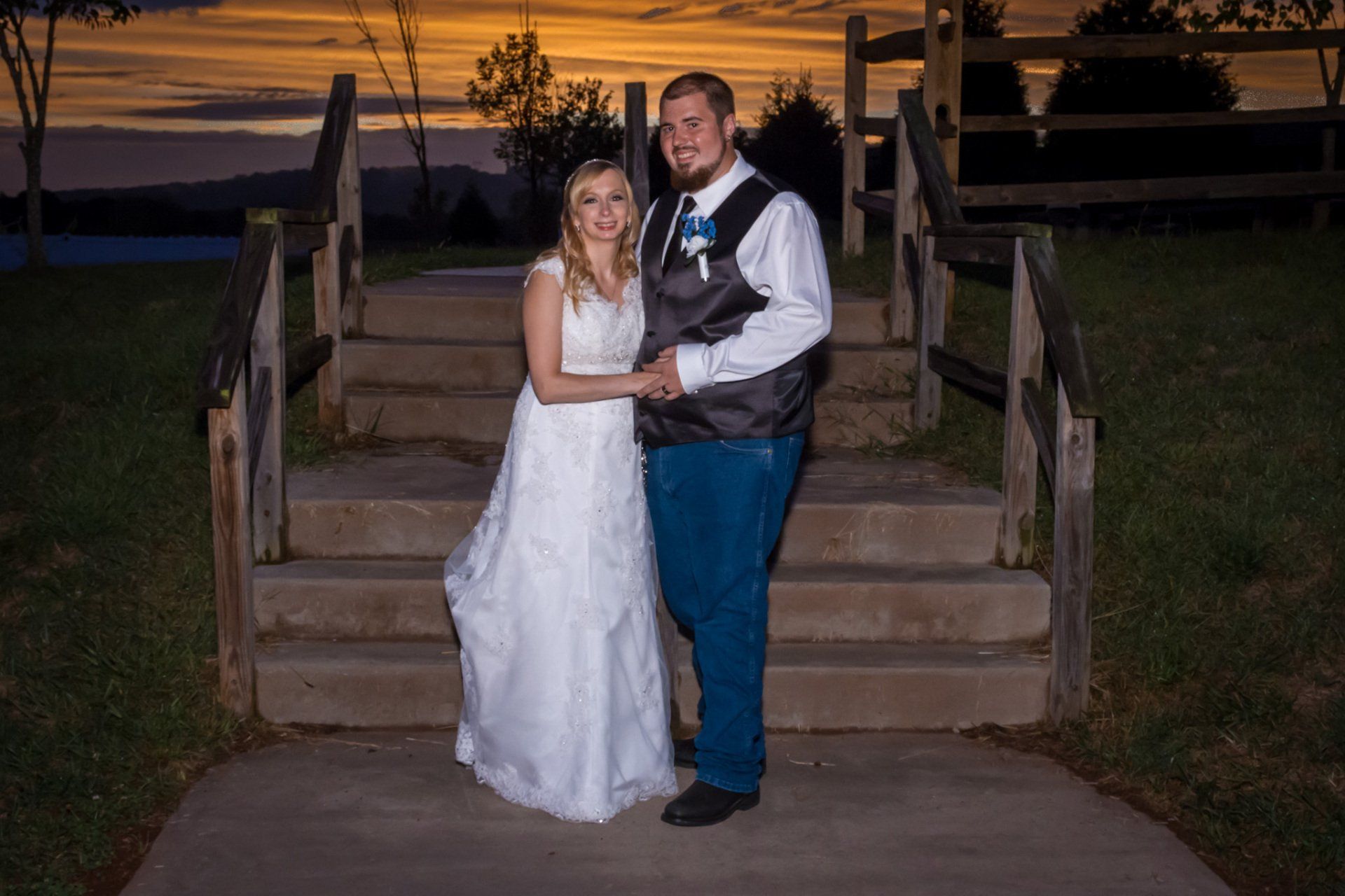 A sunset portrait of a bride and groom with a stairway and orange sunset behind them