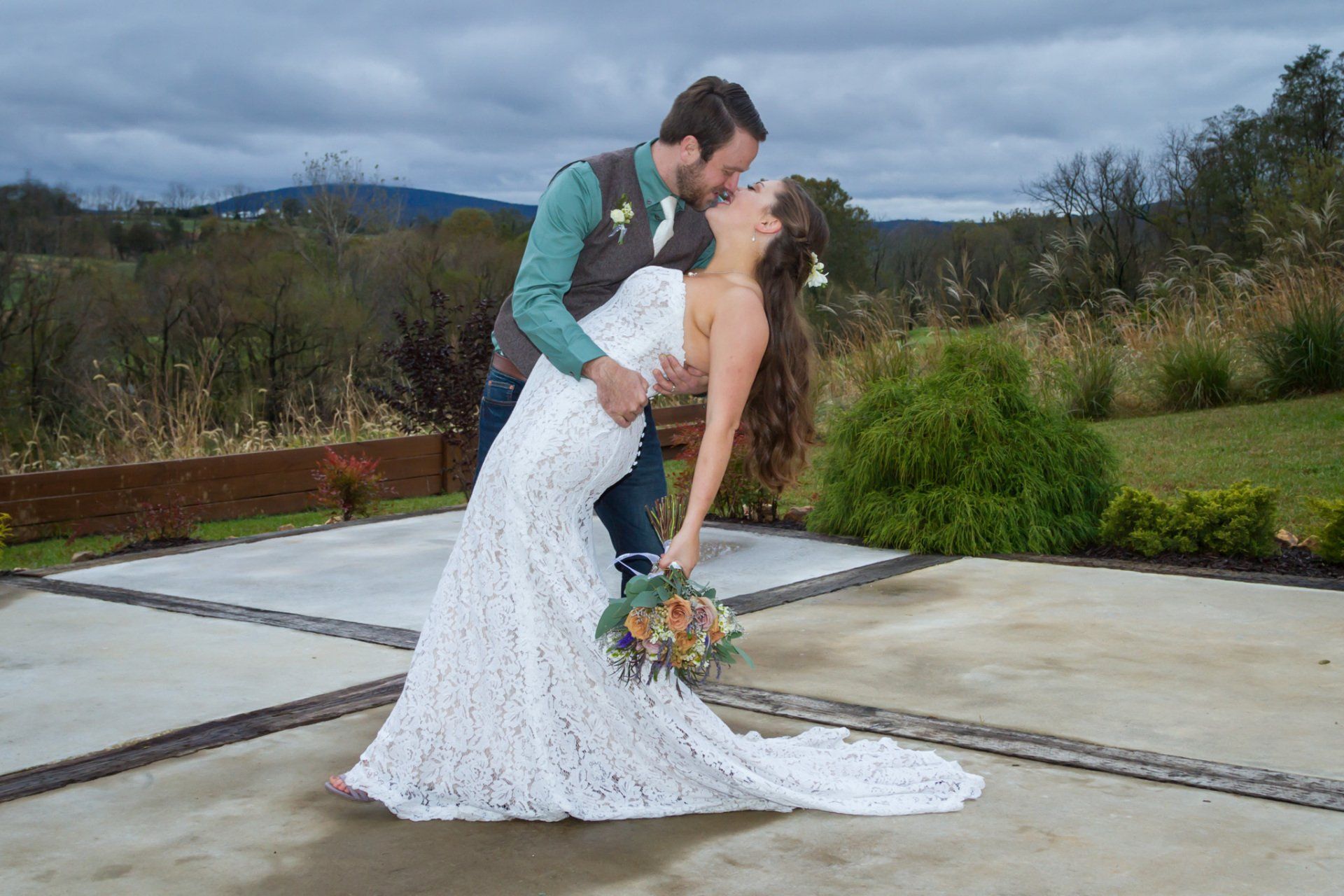 A bride and groom embracing and dipping and kissing at an outdoor venue