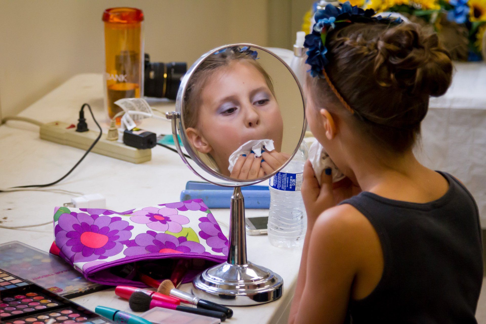 A portrait of the flower girl looking at herself in the mirror as she gets ready