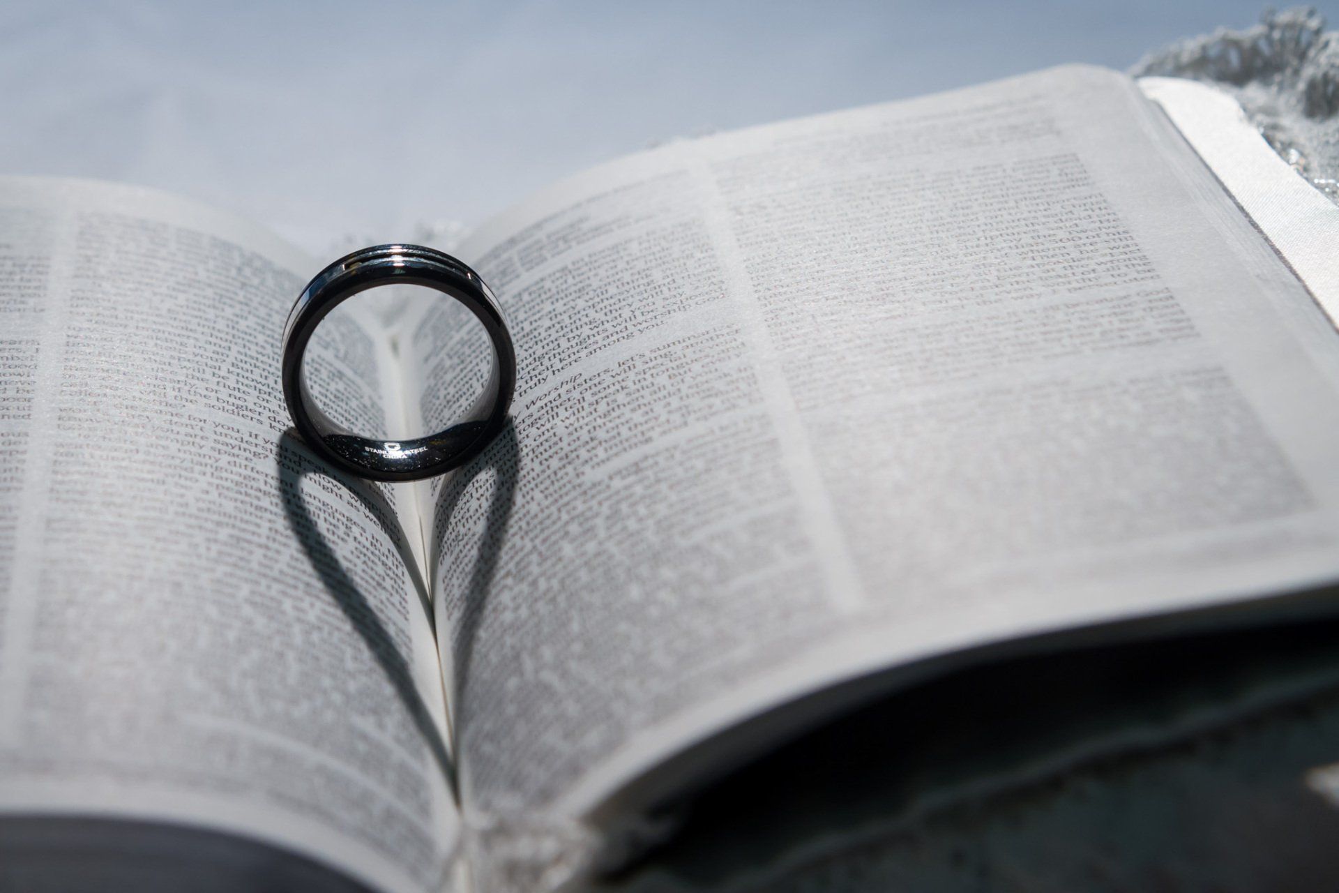An image of a wedding ring sitting in a bible with the lighting causing a heart shadow