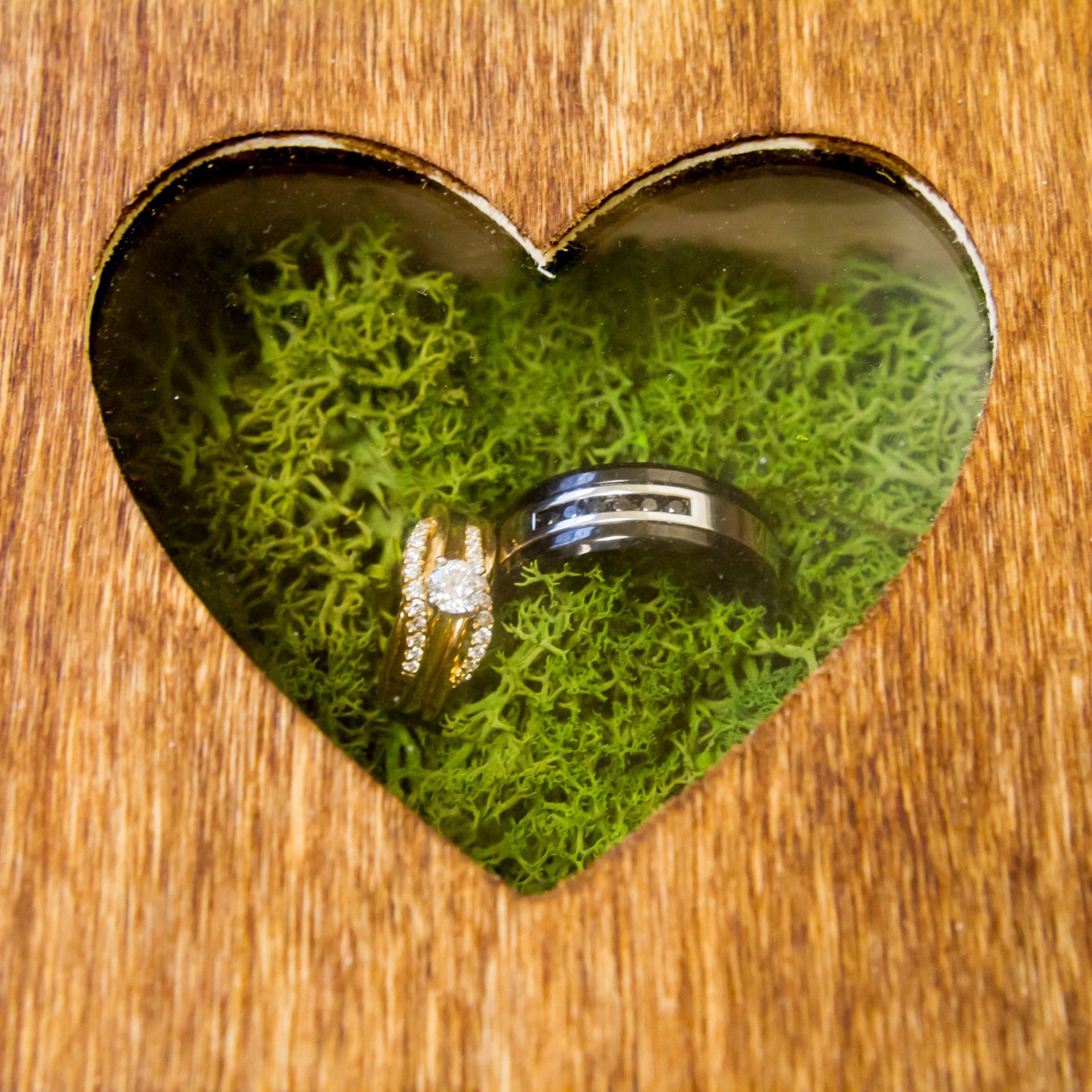 A picture of wedding rings in a wooden heart shaped box