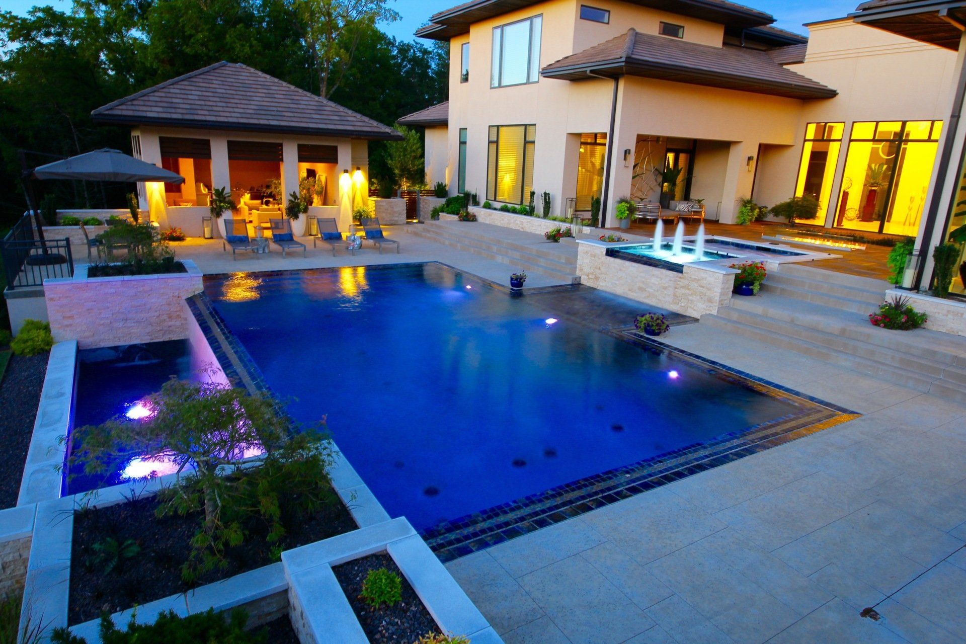 An inground pool next to large home at night