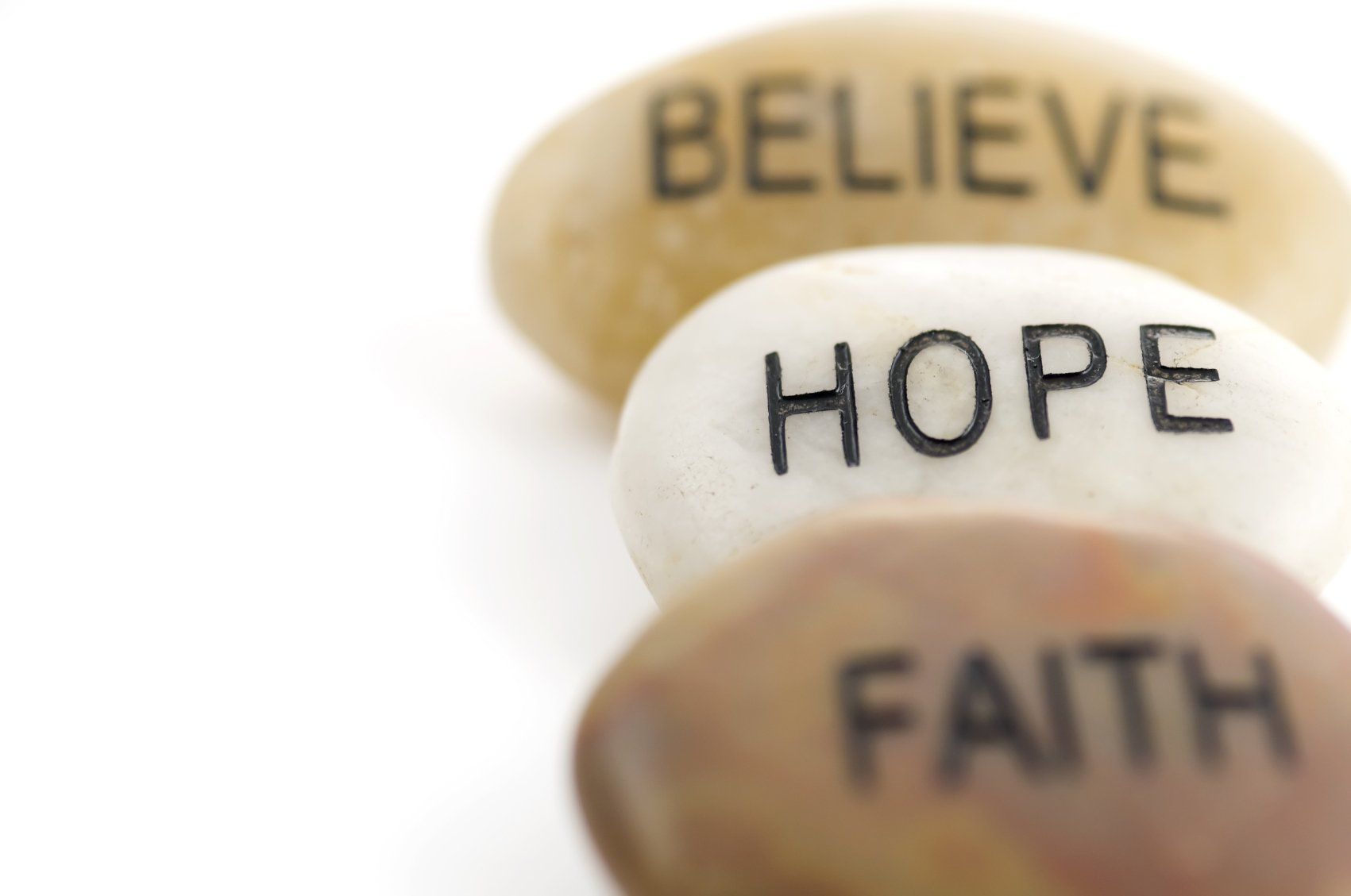 Galets avec les mots BELIEVE, HOPE et FAITH peints dessus.