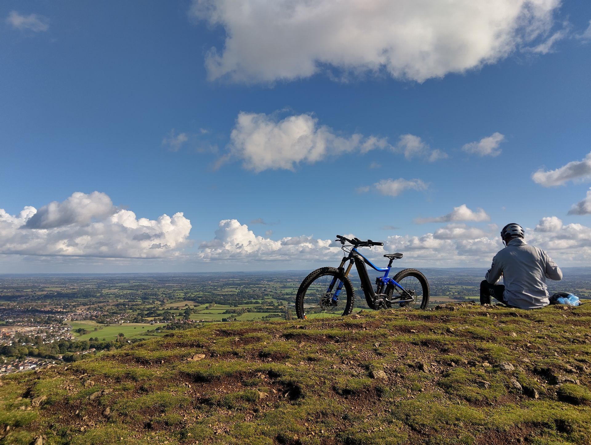 A mountain biker has a rest on top of the Malvern Hills while following the beacon trail