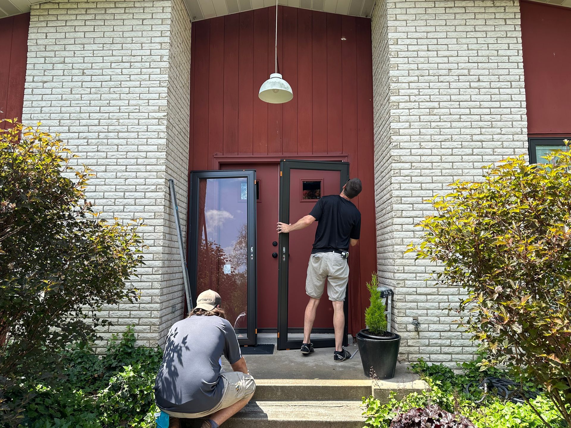 Contractors installing new modern entry door during home exterior remodel