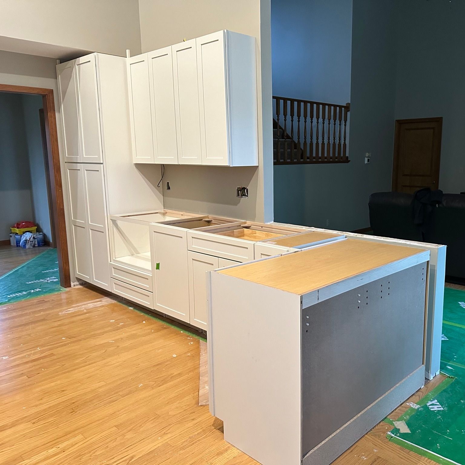 Kitchen renovation showing cabinet and island installation in progress Kitchen remodel in progress with white shaker cabinets and partially installed island by Kitchen and Bath Remodeling Plus