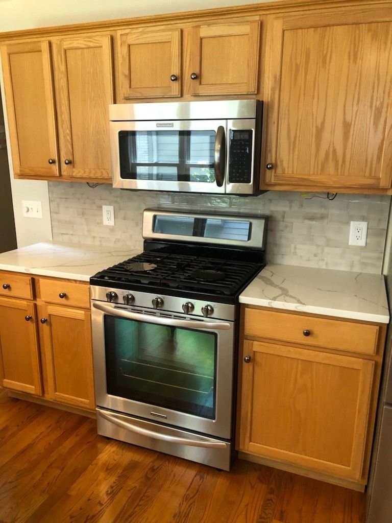 Kitchen Remodel Featuring Stainless Appliances and Natural Wood Cabinets Modern kitchen with stainless steel oven and microwave, oak cabinets, and quartz countertops