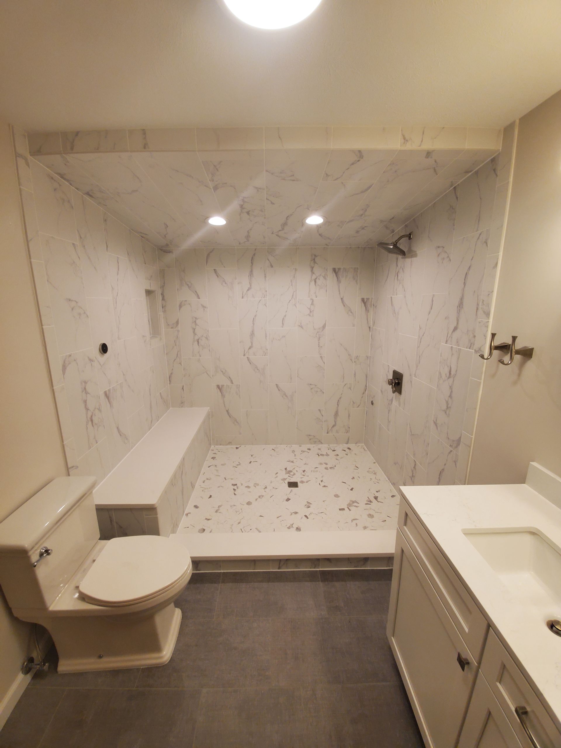 Spacious marble shower with built-in bench in a remodeled bathroom Luxury bathroom remodel with marble walk-in shower, built-in bench, and modern vanity by Kitchen and Bath Remodeling Plus