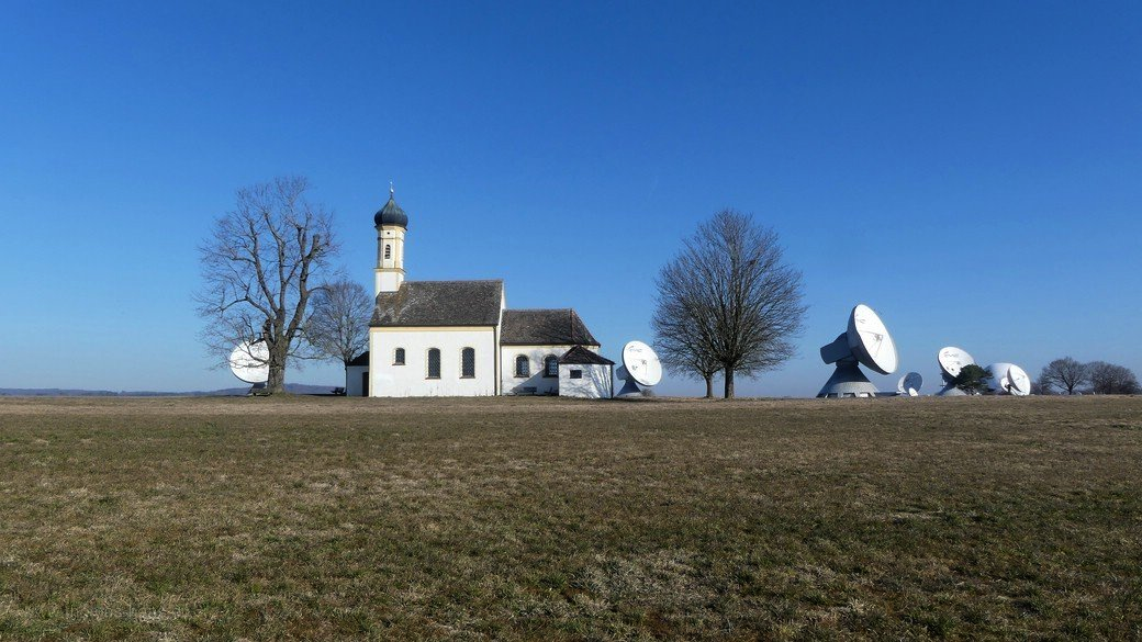Raisting, Kapelle und Parabolantennen - Bayern halt... Raisting, der Draht nach oben - so oder so...