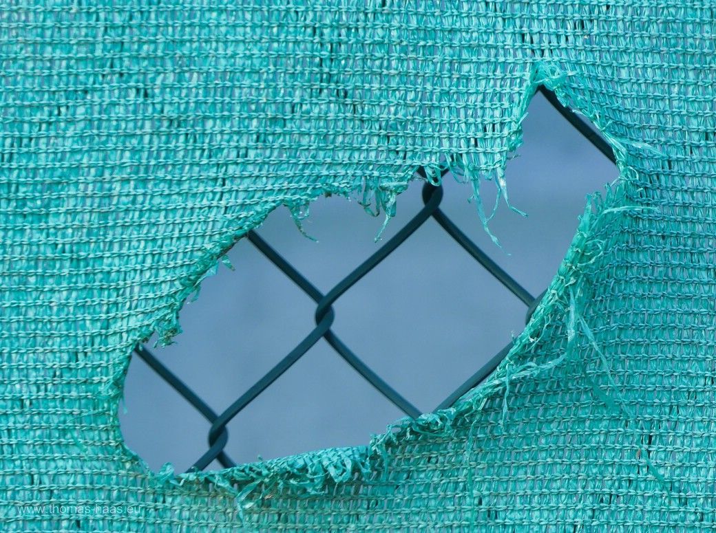 Loch im Werbebanner am Zaun der Tennis-Arena, Vöhringen, 2024 Das Zaunmotiv aus Vöhringen, ein Loch im Werbebanner an der tennis-Arena, 2024