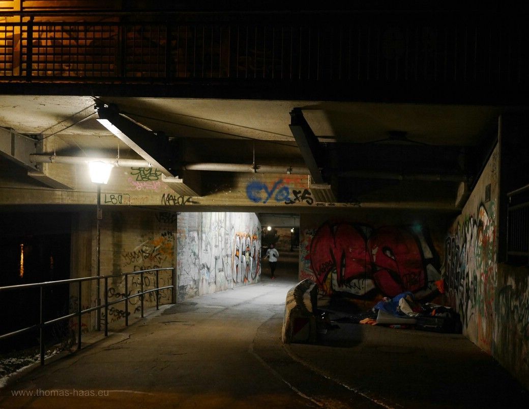 Doch die im Dunkeln sieht man nicht! Obdachlose unter der Brücke, Ulm 2023 Leben unter der Brücke, Obdachlose und ein Jogger kommt am frühen Morgen entgegen, 2023