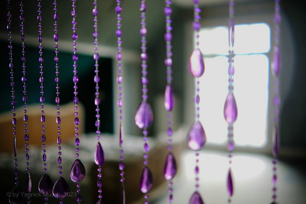 Blick durch den Perlenvorhang auf ein Hotelzimmer, © by Yannick Musch, 2023 Hotelzimmer durch einen Glasperlen-Vorhang fotografiert - Waldlust, © by Yannick Musch, 2023