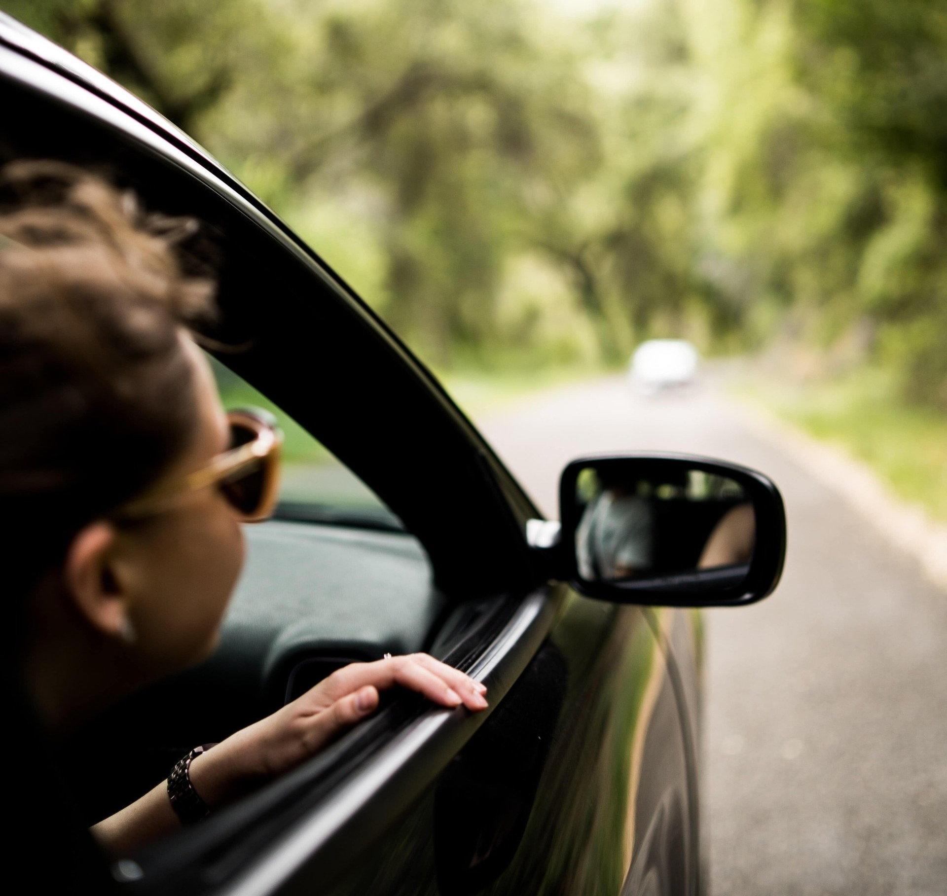 a woman wearing sunglasses with her head slightly out of a moving vehicle