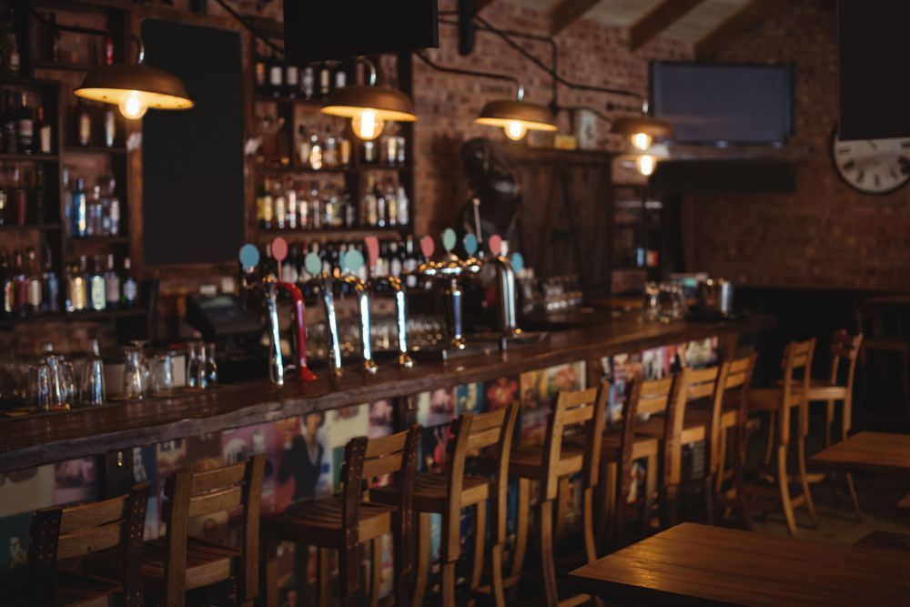 A bar featuring numerous wooden chairs and a wall clock, creating a cozy and inviting atmosphere.