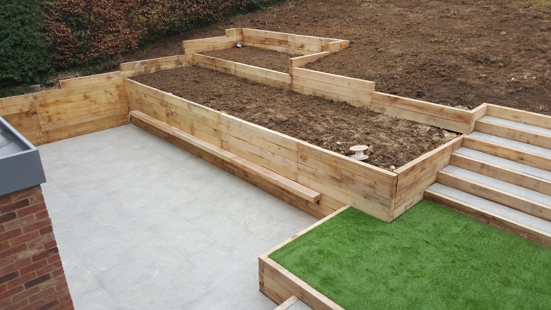 Wooden plantes, lawn installation and paving