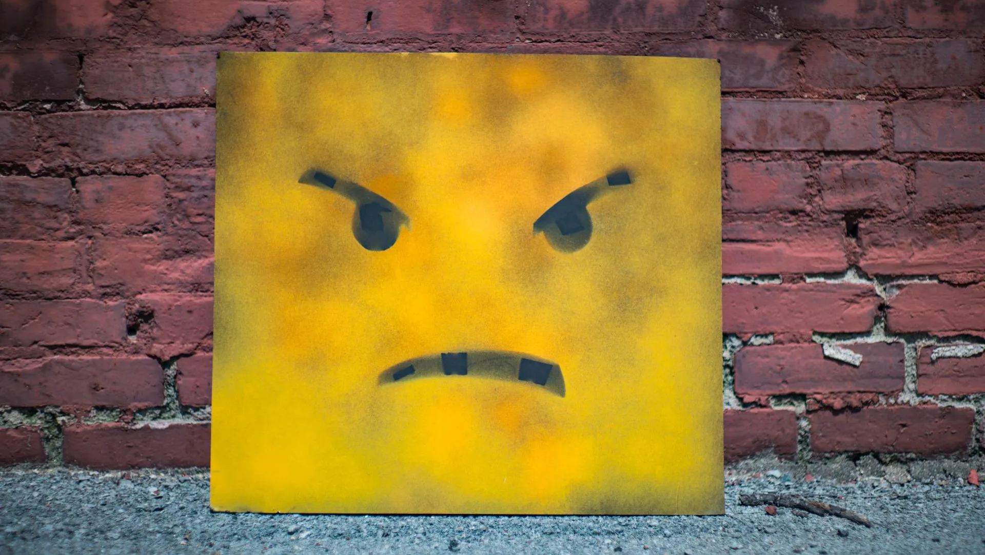 Mit strengem Gesicht und ernster Stimme warnt die Politik vor einer Verschlimmerung der Pandemie. Schild mit aufgemaltem, wütendem Gesicht vor Backsteinwand