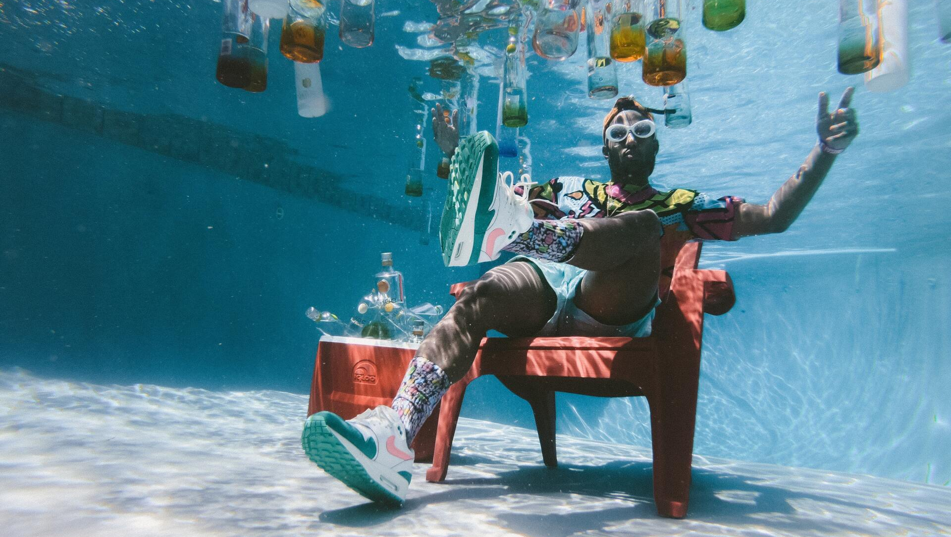 Entspannt und gut gelaunt - so feiert Südafrika sein kulturelles Erbe. Mann sitzt auf Stuhl am Grunde eines Swimingpools, im Wasser treiben bunte Flaschen