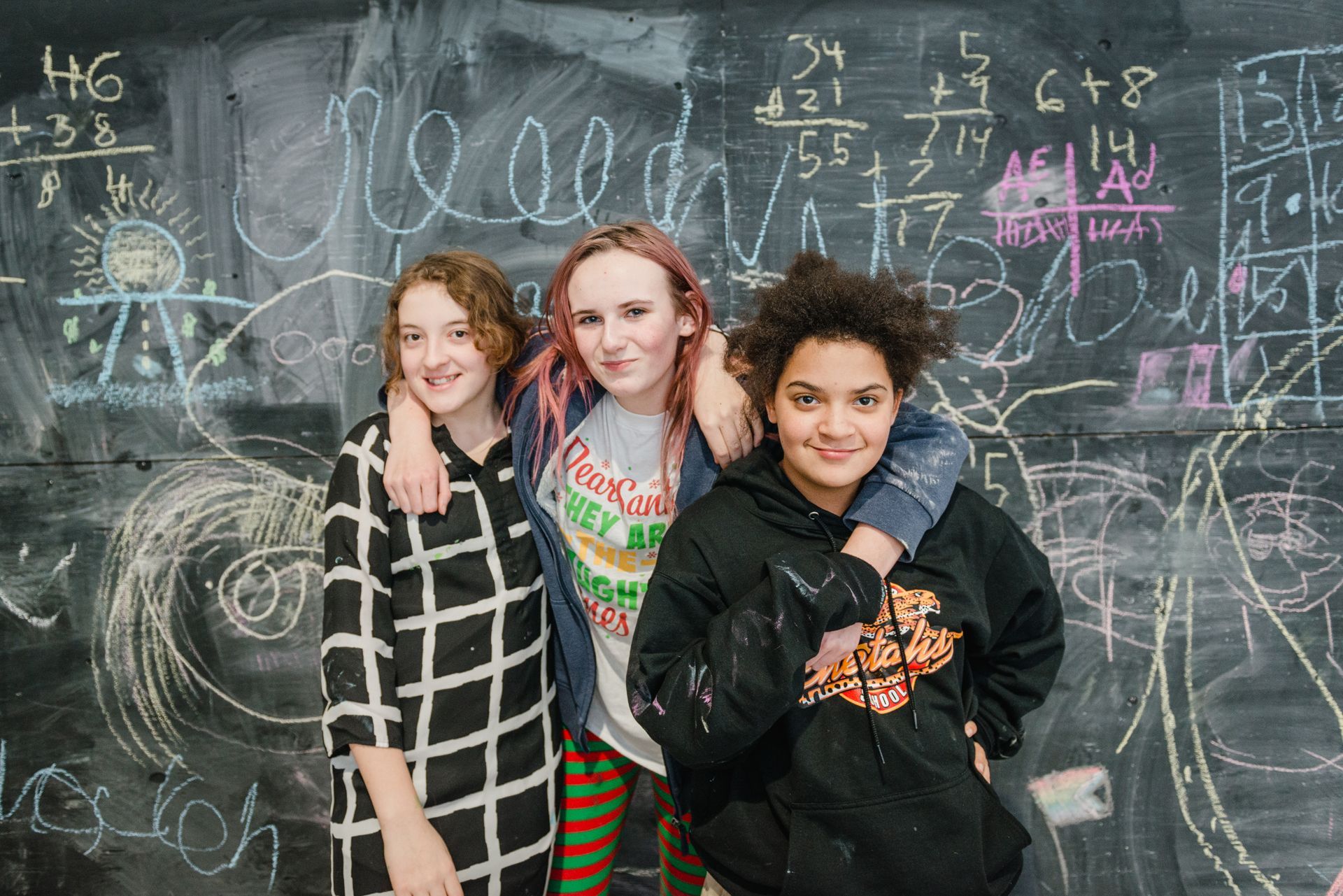 Three teens in front of a blackboard