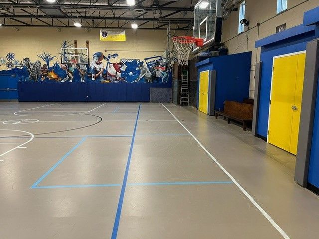 A broad view of the gym and basketball hoops.