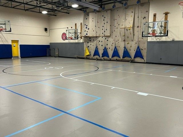 A broad view of the gym and basketball hoops.