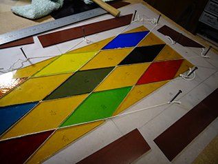 Art'lekin, vitrail sur-mesure, Arlequin, étape de restauration, coupe des pièces de verre existantes en losange et des nouvelles pièces de verre pour apporter de la variété de couleurs.