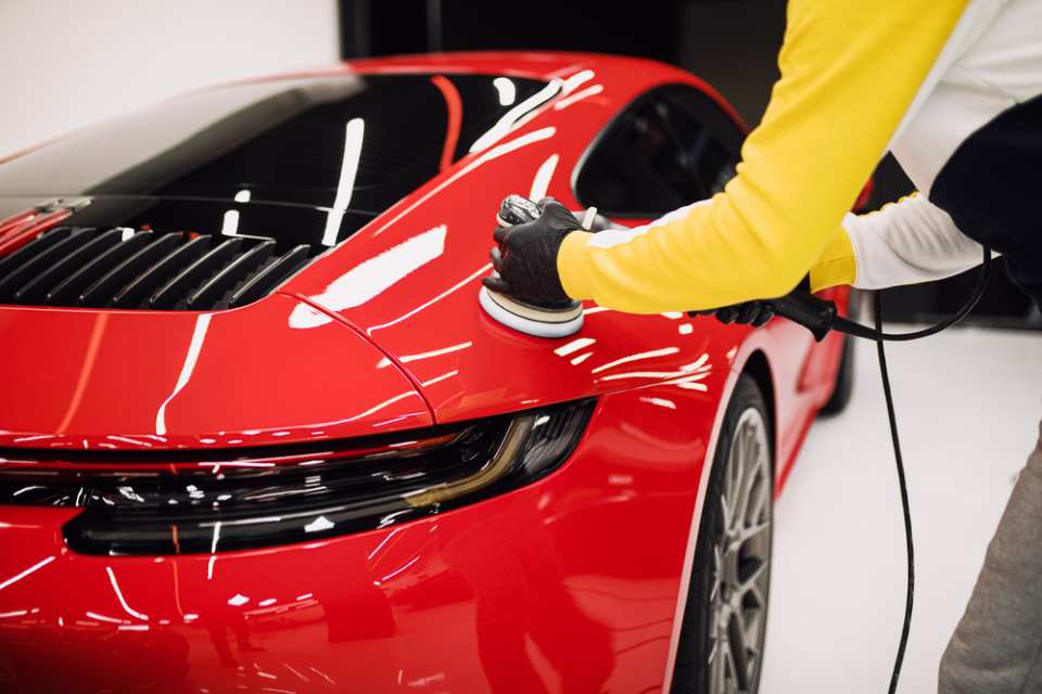 a person buffing the exterior of a red sports car