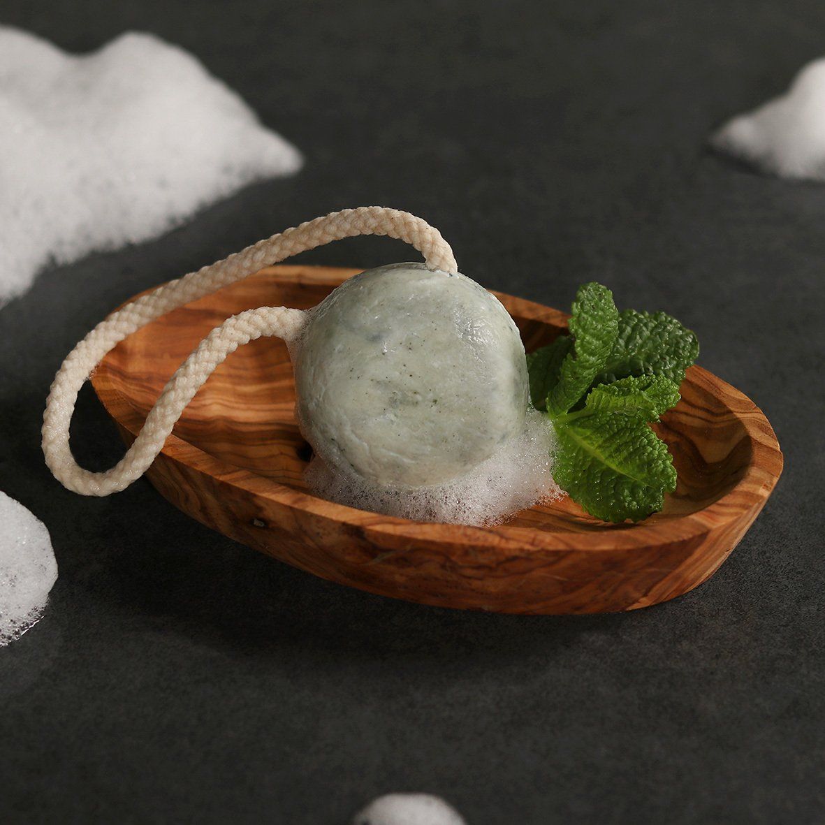 Das festes Shampoo Minze in einer Olivenholzschale mit ein paar Minzblättern