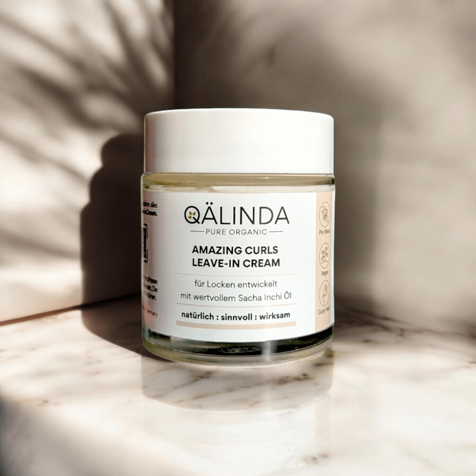 Die Amazing Curls Leave-In Cream mit Sacha Inchi Öl im Glastiegel auf einer Marmorfliese.