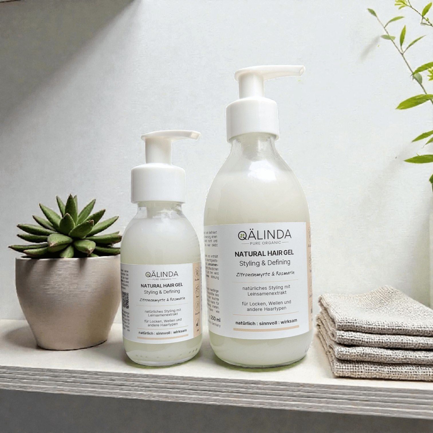 Das Natural Hair Gel mit Leinsamen Extrakt in einer kleinen und großen Glasflasche mit Pumpspender in einer natürlich eleganten Umgebung..