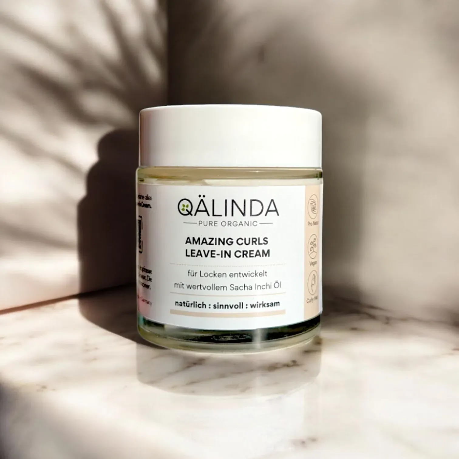 Die Amazing Curls Leave-In Cream mit Sacha Inchi Öl im Glastiegel auf einer Marmorfliese.