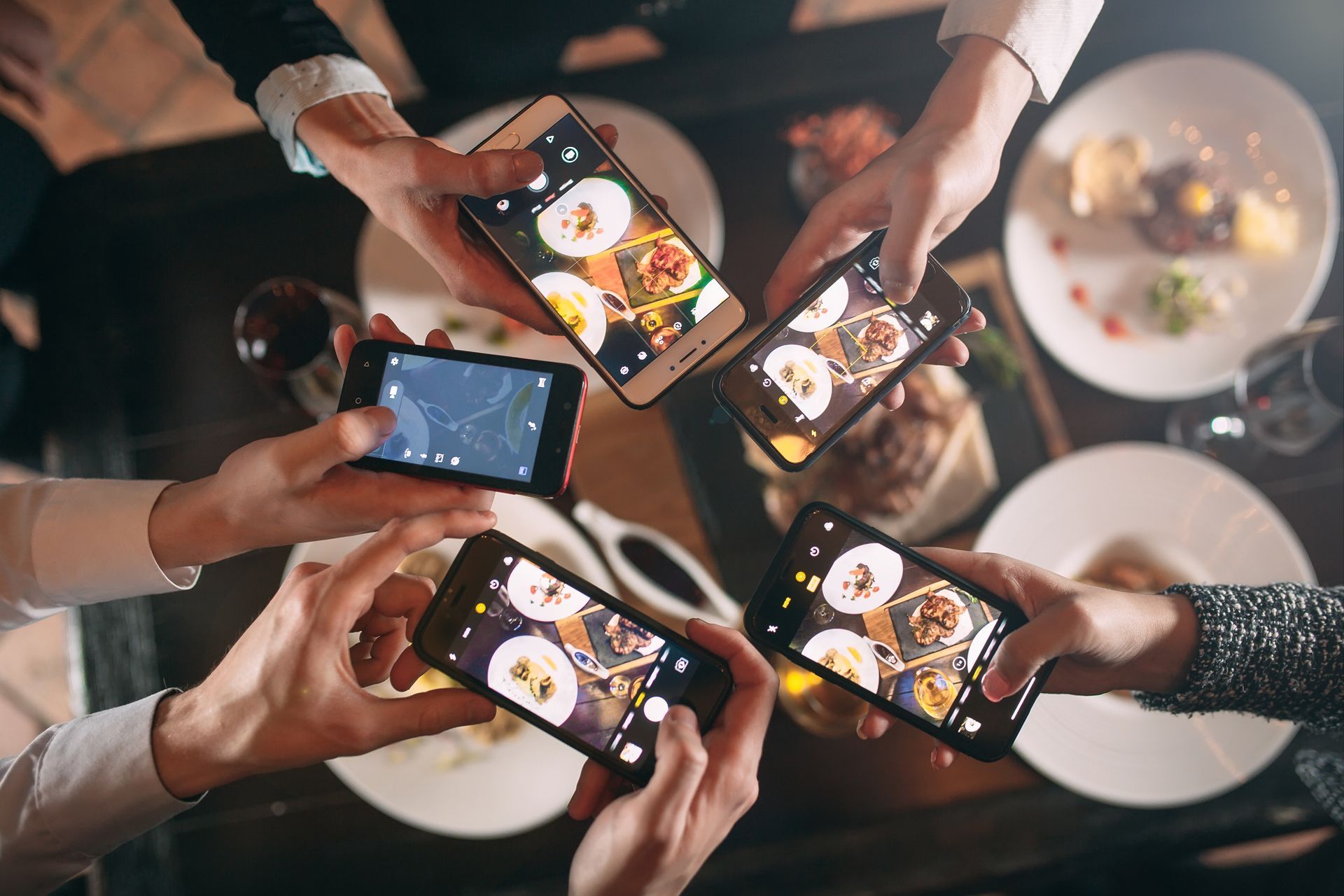 people with phones taking pictures of food in a restaurant
