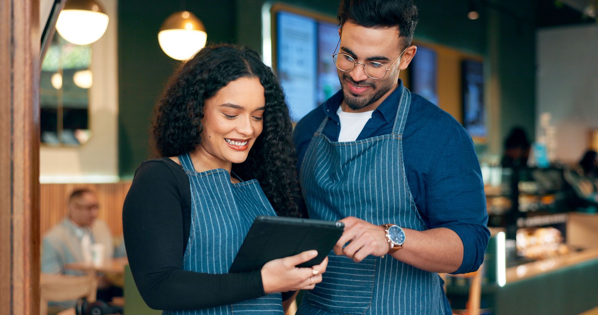 Man and woman are looking at a tablet for AI in restaurants.