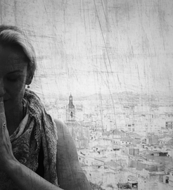 sw Foto Daniela Ferrando Ramirez Heilpraktikerin für Psychotherapie Namastehaltung Teilausschnitt frontal geschlossene Augen Hintergrund spanische Stadt gemustertes Halstuch