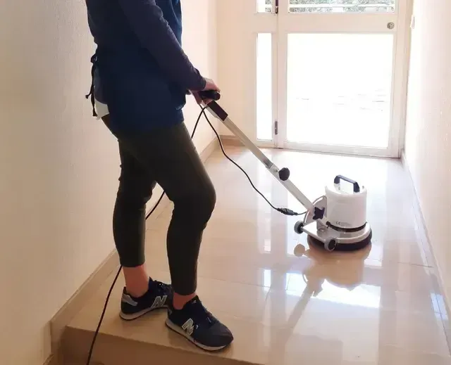 Mujer usando una máquina pulidora sobre suelo de mármol