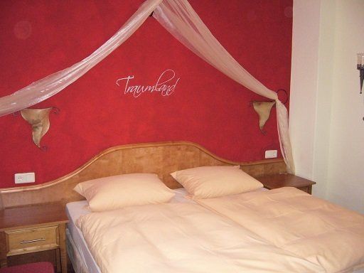 Bettschleier über einem Doppelbett in einem in rot gehaltenen Raum