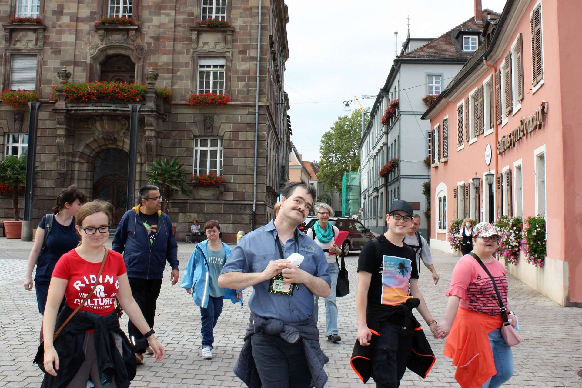 Die Clubmitglieder laufen über einen gepflasterten Platz. Im Hintergrund sind Häuser zu sehen.