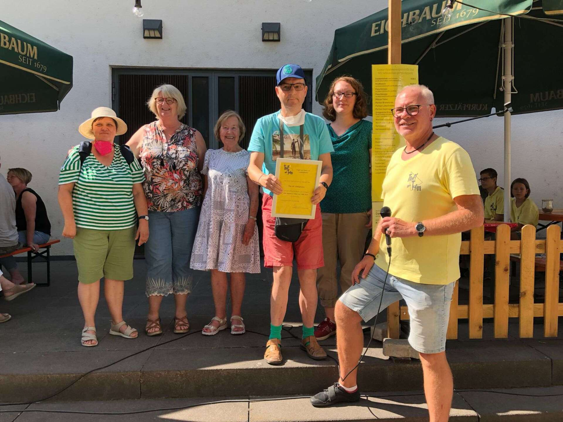 6 Menschen stehen auf einer Treppe. Einer von ihnen hält die Spendenurkunde in die Kamera.