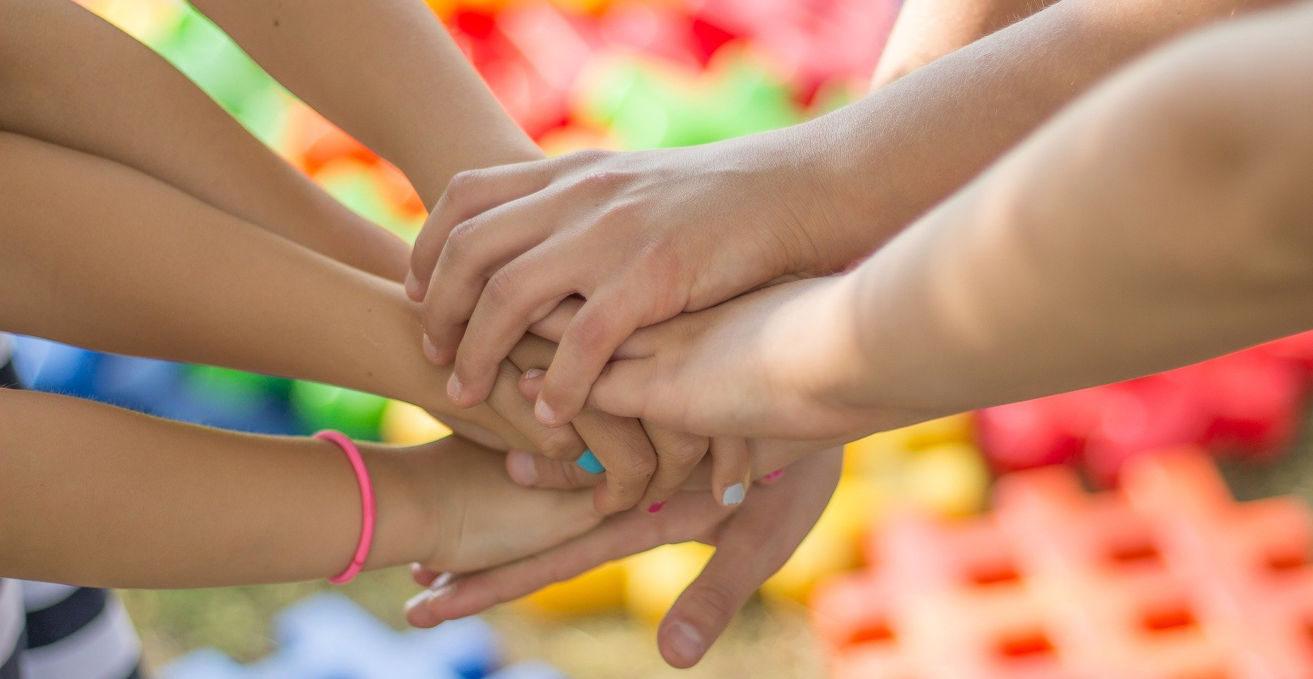 Menschen reichen sich die Hände vor buntem Hintergrund