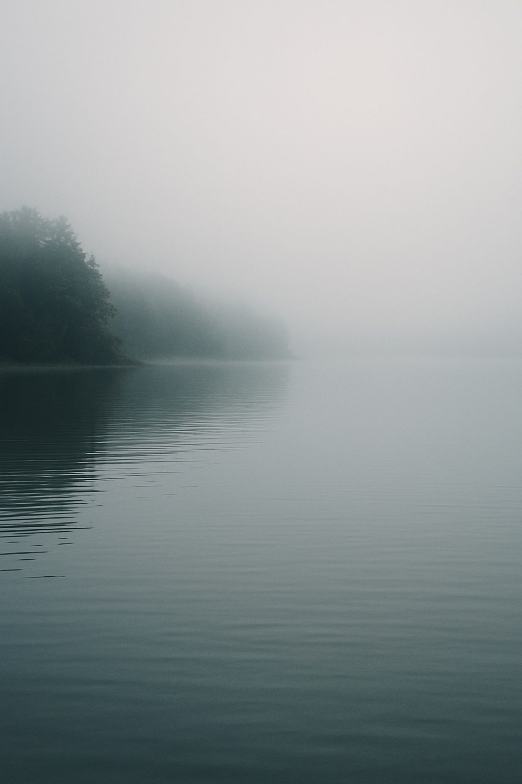 Ein nebliger See am frühen Morgen. Stille, Weite, etwas scheint verschwunden – und ist doch da